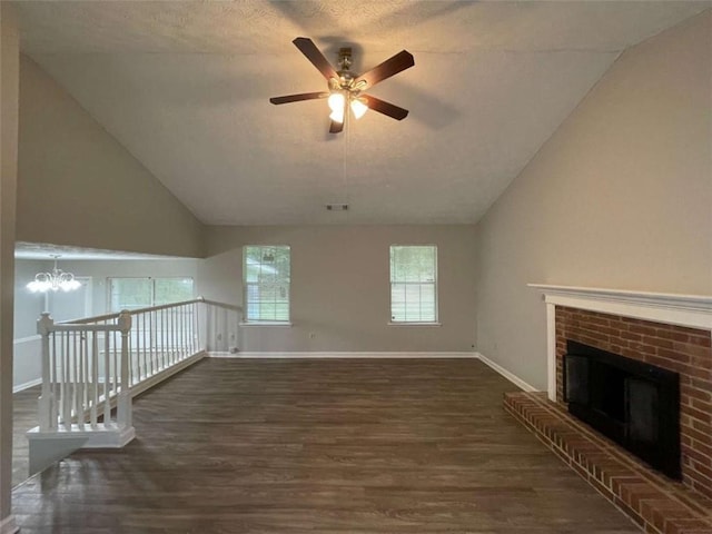 unfurnished living room with ceiling fan with notable chandelier, vaulted ceiling, dark hardwood / wood-style floors, a textured ceiling, and a fireplace