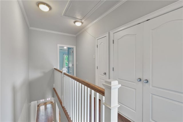 hallway featuring dark wood-style floors, crown molding, and an upstairs landing