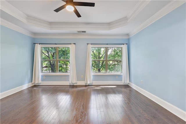 empty room featuring a tray ceiling, wood-type flooring, visible vents, and plenty of natural light