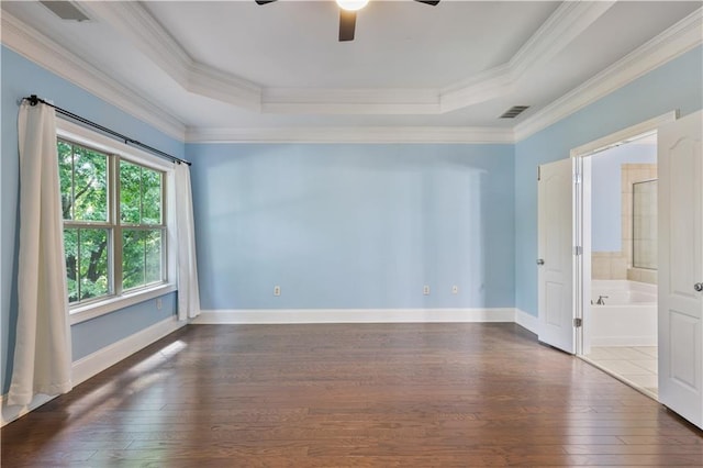 empty room with visible vents, a tray ceiling, hardwood / wood-style floors, and crown molding