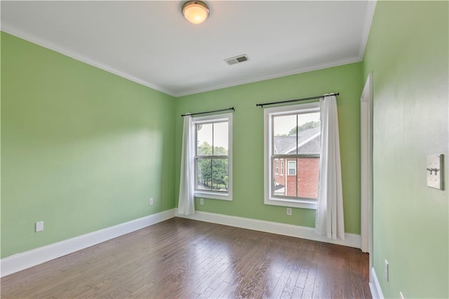 empty room with visible vents, baseboards, wood finished floors, and ornamental molding