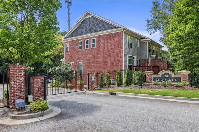 view of side of property with a gate, brick siding, and fence