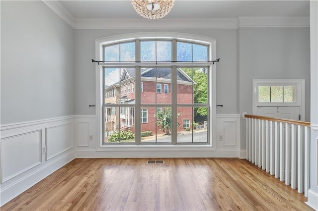 doorway to outside with ornamental molding, visible vents, and light wood finished floors