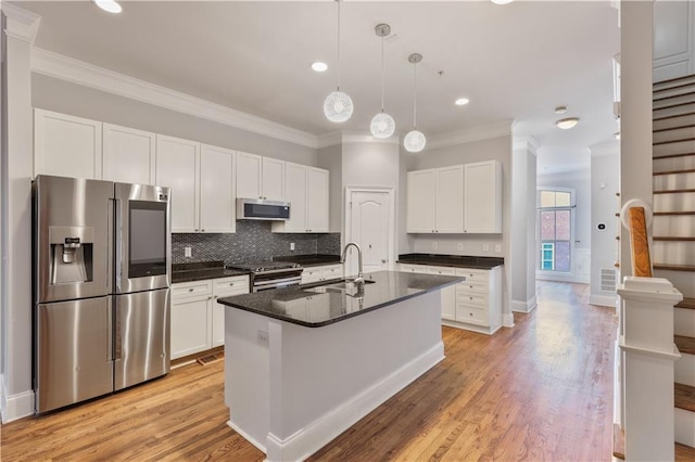 kitchen with stainless steel appliances, a sink, white cabinetry, backsplash, and dark countertops