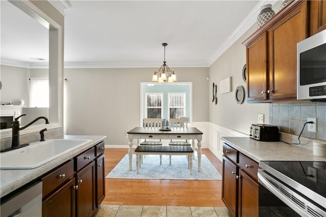 kitchen with a sink, a chandelier, crown molding, and appliances with stainless steel finishes