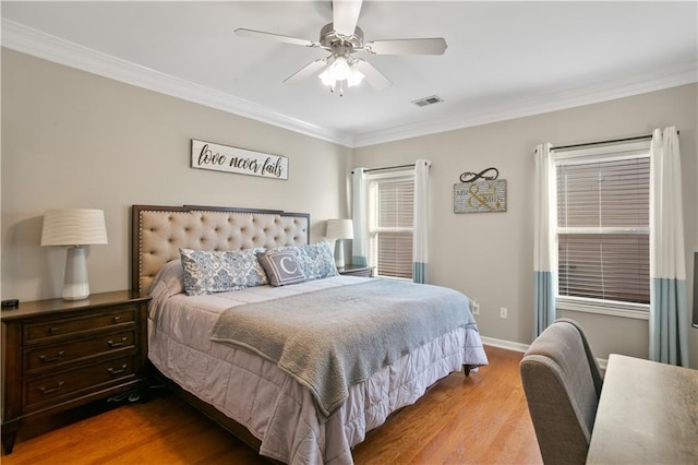 bedroom featuring visible vents, baseboards, ornamental molding, wood finished floors, and a ceiling fan