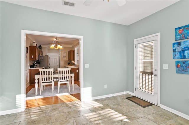 interior space with baseboards, visible vents, crown molding, and ceiling fan with notable chandelier
