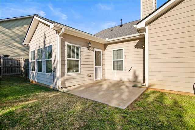 rear view of property with a yard, a chimney, fence, and a patio area