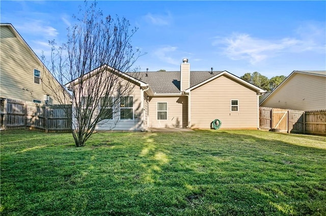 back of property with a chimney, roof with shingles, a fenced backyard, a yard, and a patio area