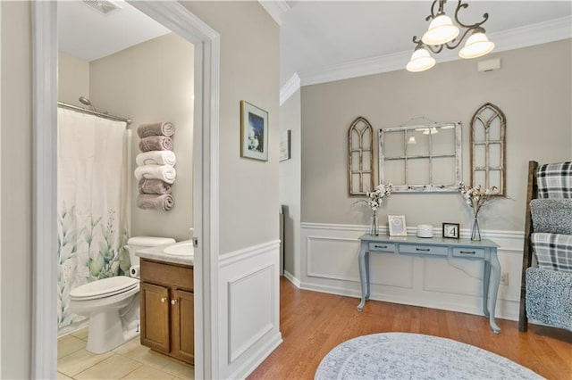 bathroom with a wainscoted wall, ornamental molding, visible vents, and vanity