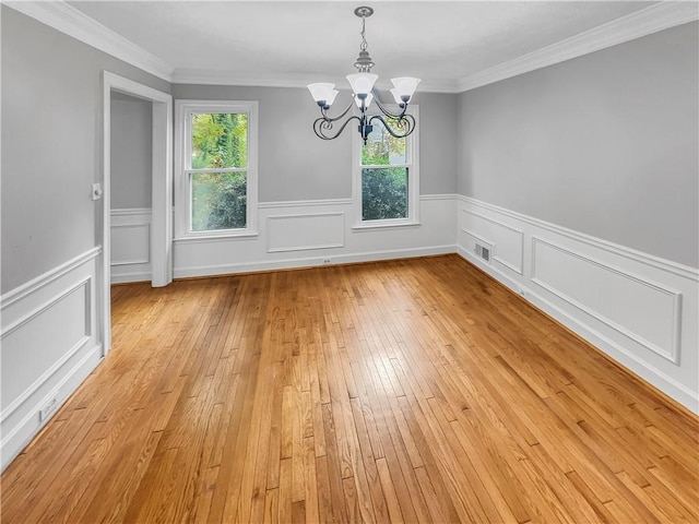 unfurnished dining area featuring light hardwood / wood-style floors, crown molding, and an inviting chandelier