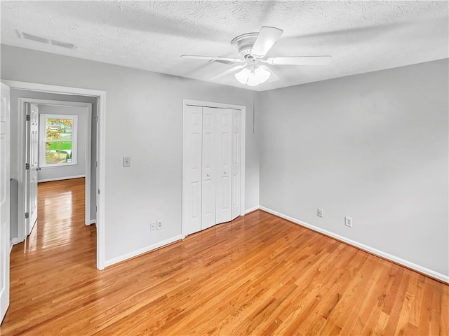 unfurnished bedroom with ceiling fan, a closet, a textured ceiling, and light wood-type flooring