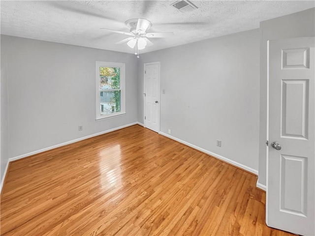 spare room featuring ceiling fan, light hardwood / wood-style floors, and a textured ceiling