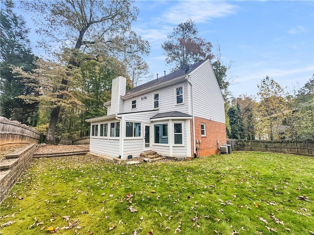 rear view of property with a sunroom, cooling unit, and a lawn