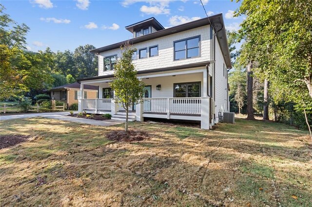 view of front facade featuring a front lawn, covered porch, and central AC