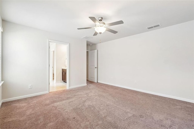 unfurnished bedroom featuring light colored carpet, ensuite bath, and ceiling fan