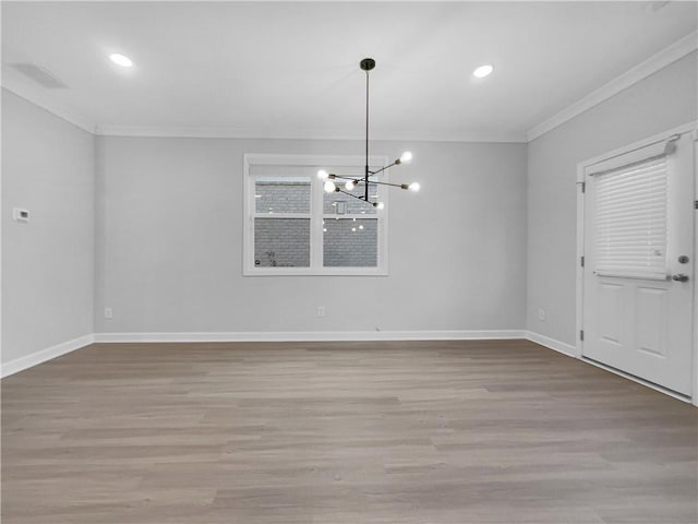 unfurnished dining area featuring an inviting chandelier, wood finished floors, baseboards, and ornamental molding