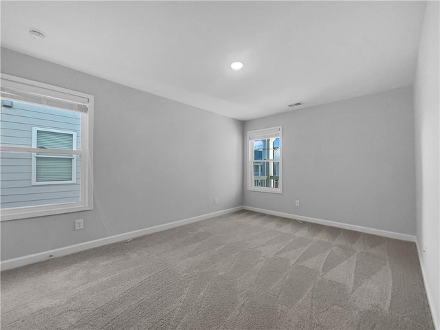 carpeted empty room featuring visible vents and baseboards