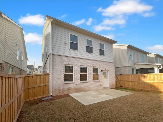 rear view of house with a patio, a fenced backyard, and brick siding