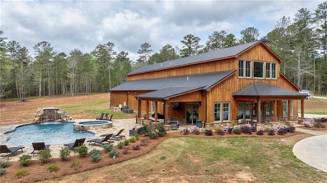 back of property featuring pool water feature, a patio area, a yard, and a swimming pool with hot tub