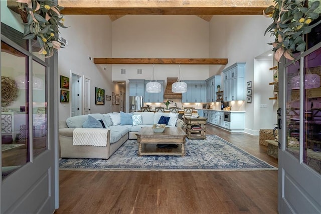 living room featuring a high ceiling, dark hardwood / wood-style floors, and beamed ceiling