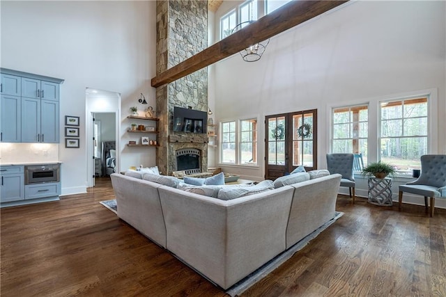 living room featuring a stone fireplace, a high ceiling, and dark hardwood / wood-style flooring