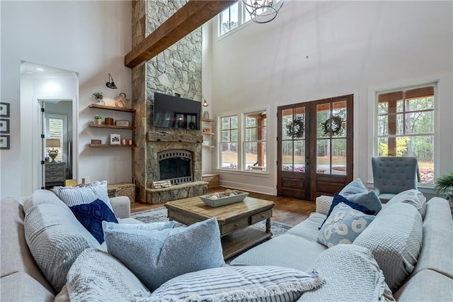 living room featuring hardwood / wood-style flooring, a high ceiling, and a stone fireplace