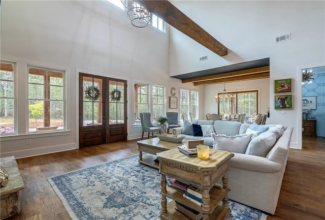 living room with french doors, a towering ceiling, dark hardwood / wood-style floors, a notable chandelier, and beamed ceiling