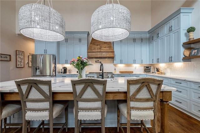 kitchen with appliances with stainless steel finishes, an island with sink, tasteful backsplash, a chandelier, and a breakfast bar area