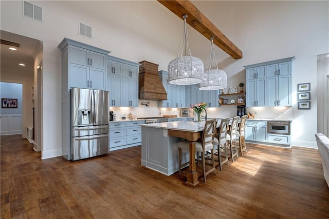 kitchen with a center island, premium range hood, backsplash, stainless steel fridge, and beam ceiling