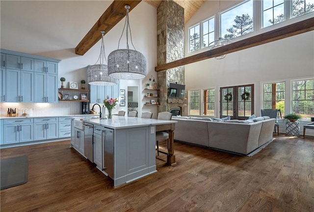 kitchen with high vaulted ceiling, hanging light fixtures, a center island with sink, and a kitchen breakfast bar