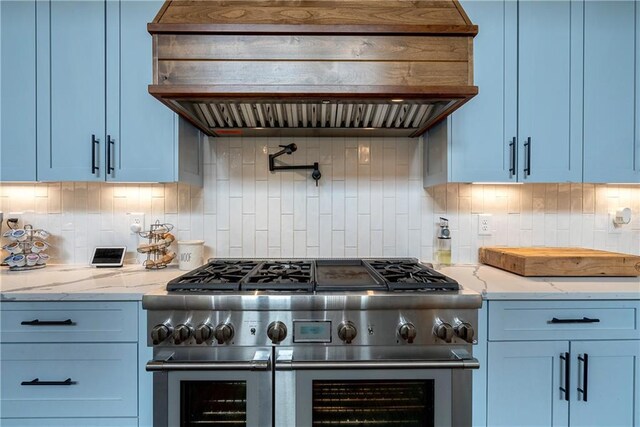 kitchen with light stone counters, backsplash, range with two ovens, and custom exhaust hood