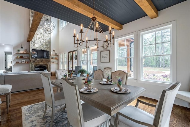 dining area featuring a notable chandelier, a stone fireplace, wooden ceiling, beam ceiling, and dark hardwood / wood-style floors