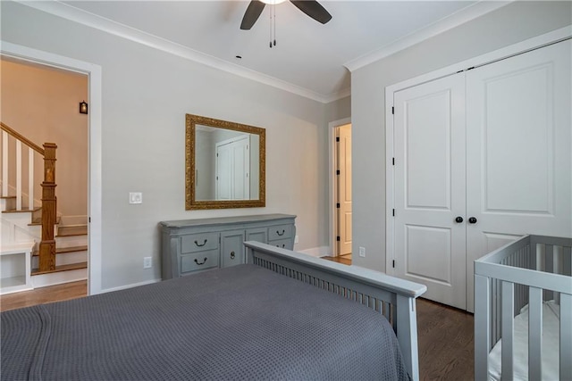 unfurnished bedroom featuring crown molding, ceiling fan, a nursery area, dark hardwood / wood-style flooring, and a closet