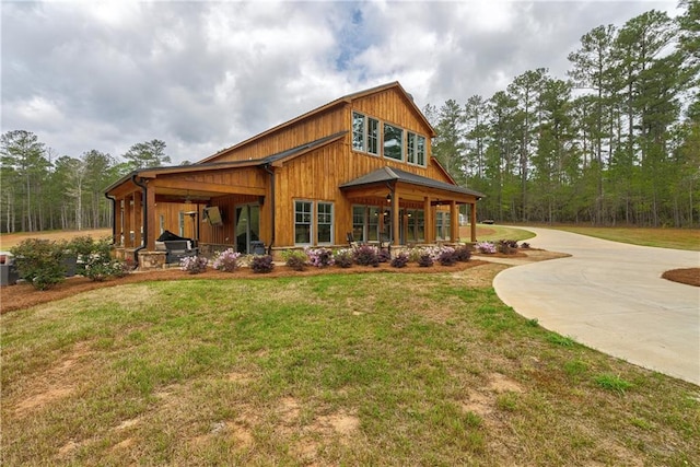 rear view of property featuring covered porch and a lawn