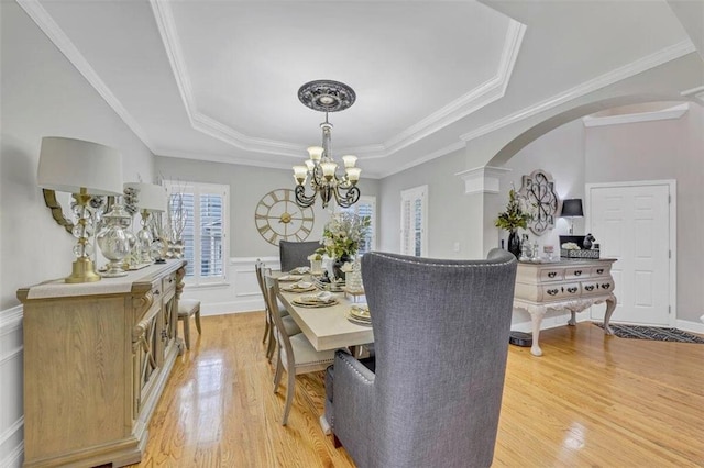 dining room with a raised ceiling, an inviting chandelier, light hardwood / wood-style floors, and ornamental molding