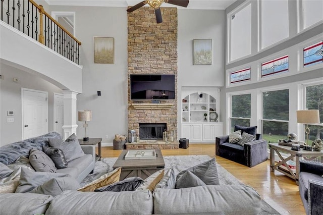 living room with light hardwood / wood-style floors, a stone fireplace, and a towering ceiling