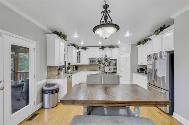 kitchen featuring decorative light fixtures, tasteful backsplash, white cabinetry, stainless steel appliances, and light hardwood / wood-style flooring