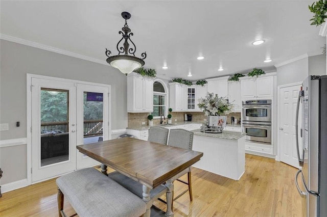 dining room featuring sink, light wood-type flooring, ornamental molding, and french doors