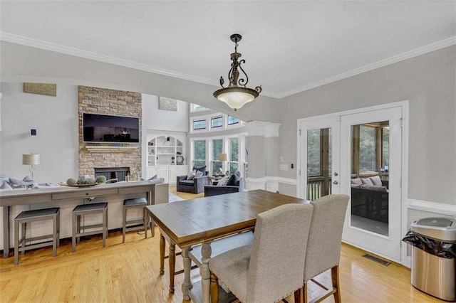 dining space with a fireplace, ornamental molding, light hardwood / wood-style floors, and plenty of natural light