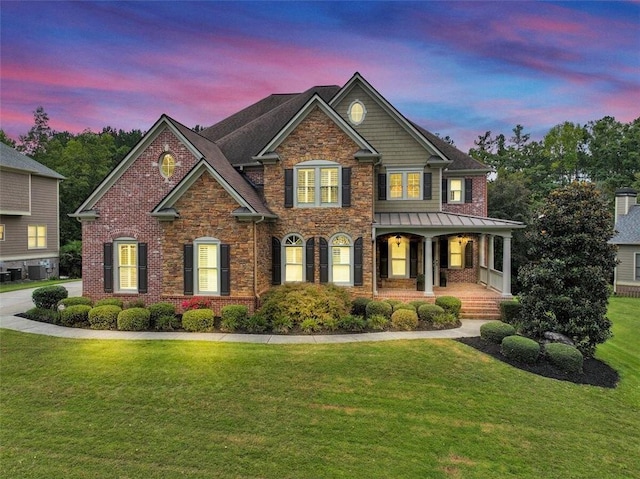 craftsman-style house featuring covered porch, central AC unit, and a lawn