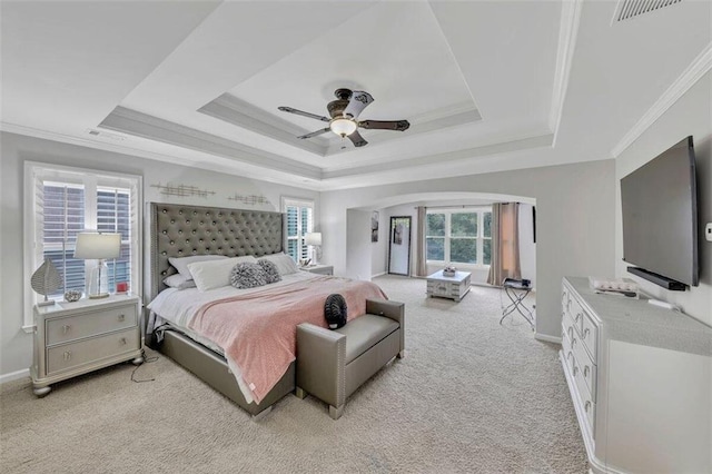 carpeted bedroom with ceiling fan, a raised ceiling, and ornamental molding