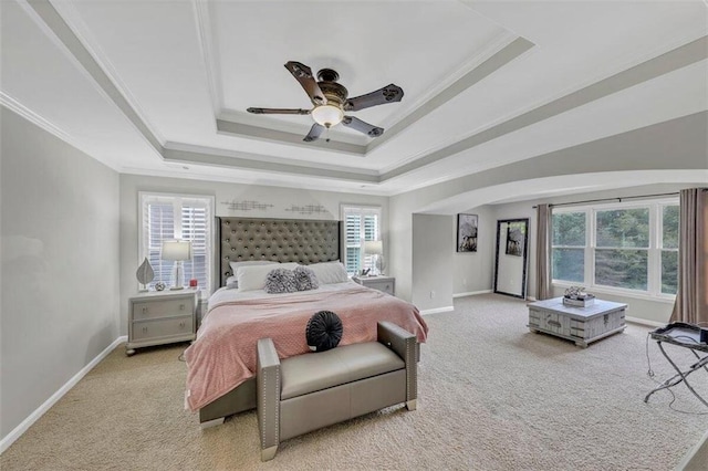 carpeted bedroom with a raised ceiling, crown molding, and ceiling fan