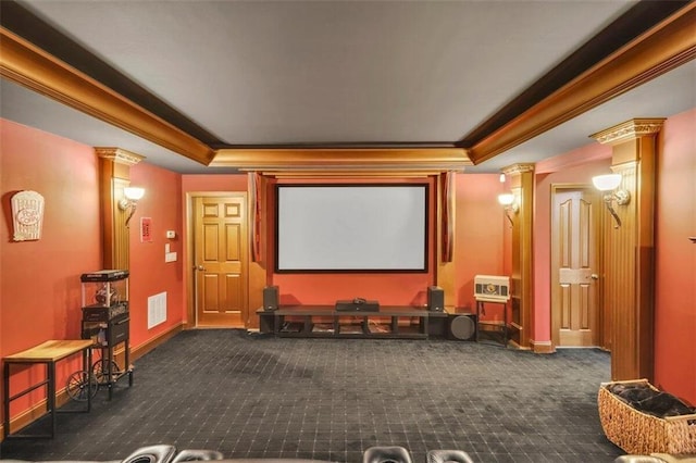 cinema featuring a tray ceiling, crown molding, dark colored carpet, and ornate columns