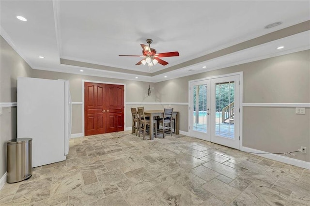 unfurnished living room featuring light tile floors, a raised ceiling, ceiling fan, and french doors