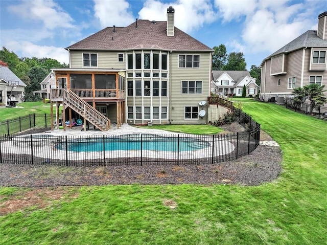 view of swimming pool featuring a sunroom, a wooden deck, and a yard