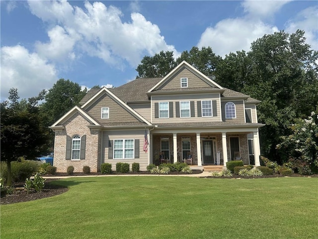 view of front facade featuring brick siding, a porch, and a front yard