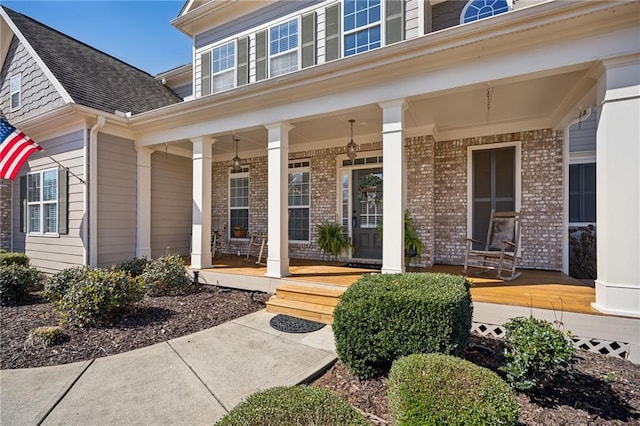 entrance to property featuring covered porch and brick siding