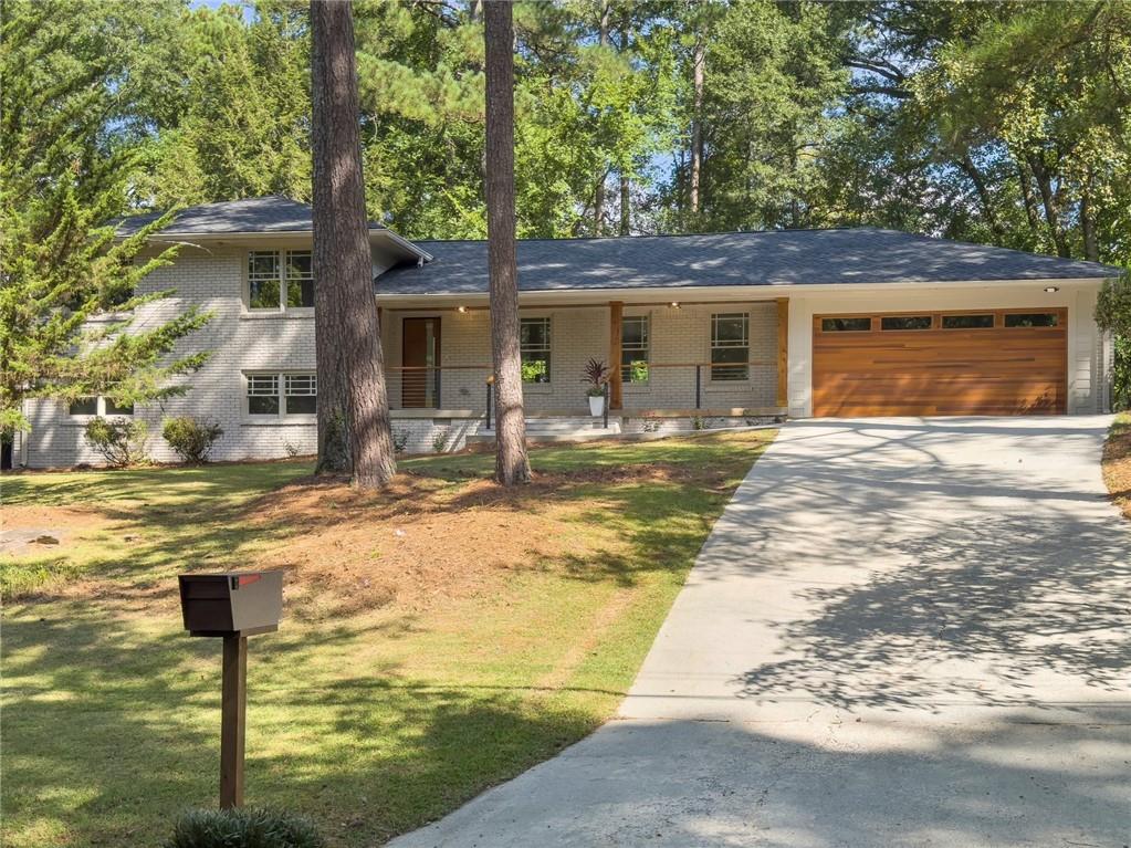 view of front of property featuring a garage, a porch, and a front yard