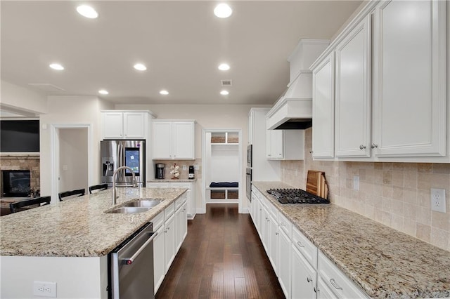 kitchen with stainless steel appliances, an island with sink, sink, and white cabinets